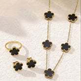 Jewelry set with black clover-shaped pendants on gold chains.