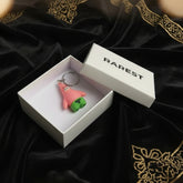 Pink cartoon character keychain on a blue fabric background